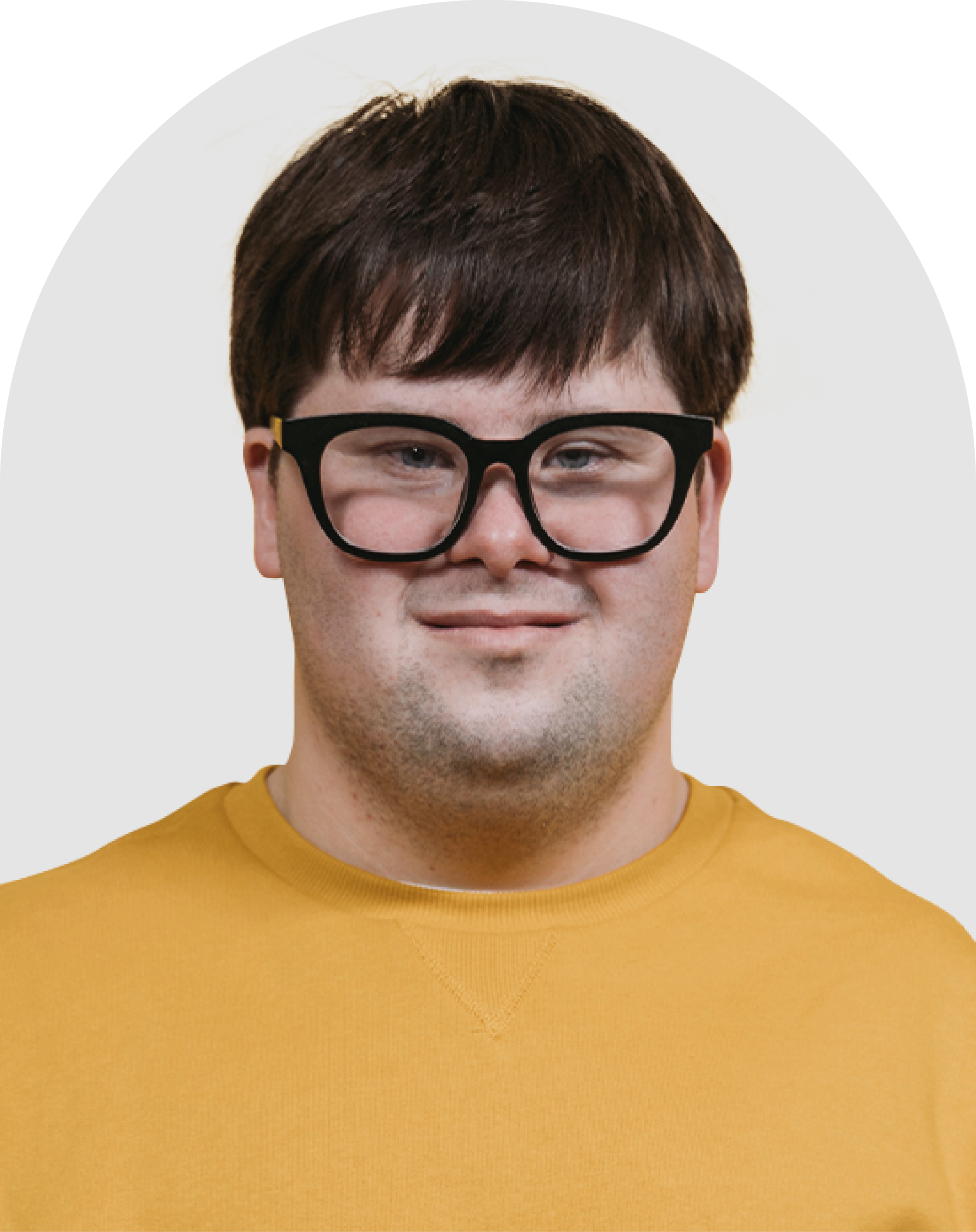 Foto de um homem branco com síndrome de down. Ele usa óculos de grau preto e uma camiseta amarela.